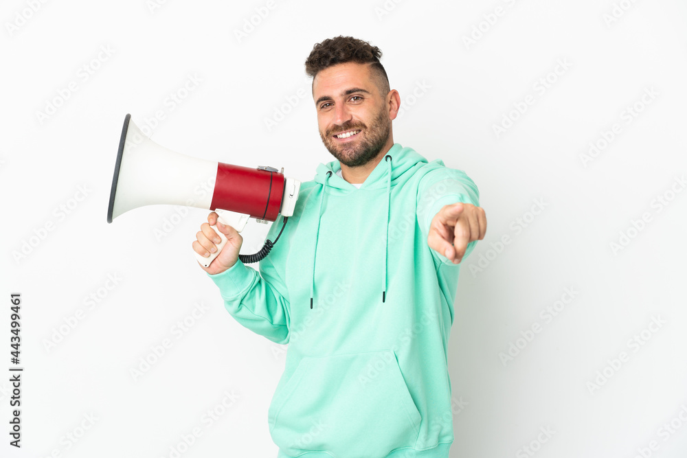 Caucasian man isolated on white background holding a megaphone and smiling while pointing to the front Caucasian man isolated on white background holding a megaphone and smiling while pointing to the front