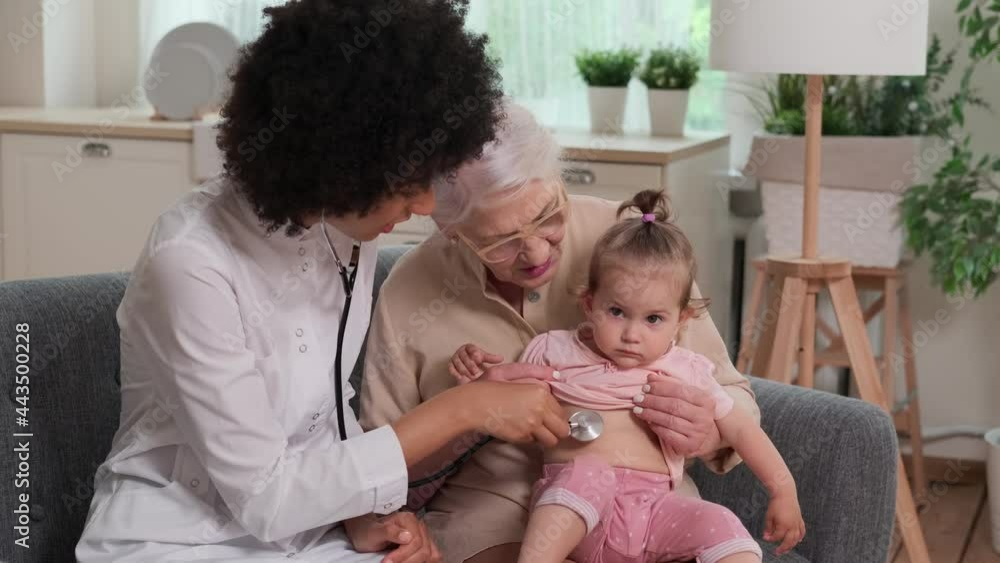Afro american woman doctor while examining family of grandmother and toddler. Family Doctor, Patient Support, Help at Home, Caring for the Sick. Afro american woman doctor while examining family of grandmother and toddler. Family Doctor, Patient Support, Help at Home, Caring for the Sick.
