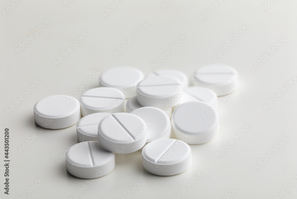 a handful of round white pills on a white table close-up, macro, medical background a handful of round white pills on a white table close-up, macro, medical background