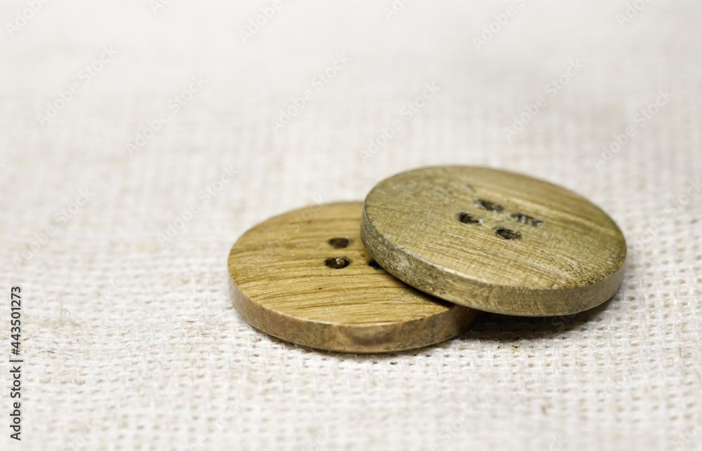 two wooden buttons lie on burlap, side view, close-up .selective focus.High quality photo two wooden buttons lie on burlap, side view, close-up .selective focus.High quality photo