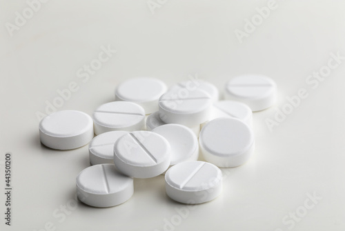 a handful of round white pills on a white table close-up  macro  medical background
