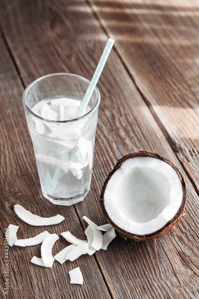 A glass of fresh organic coconut water, milk on a wooden table and a ripe half of a coconut nearby. Refreshing vegetarian drinks A glass of fresh organic coconut water, milk on a wooden table and a ripe half of a coconut nearby. Refreshing vegetarian drinks