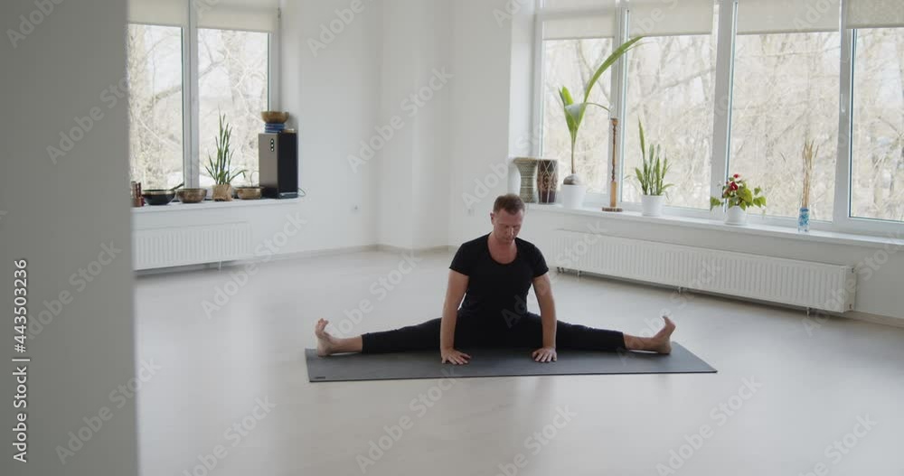 Professional trainer practices flow yoga in private class. Adult man makes yoga asanas on a mat in white bright studio. Fitness, healthy lifestyle and wellness concept. Professional trainer practices flow yoga in private class. Adult man makes yoga asanas on a mat in white bright studio. Fitness, healthy lifestyle and wellness concept.