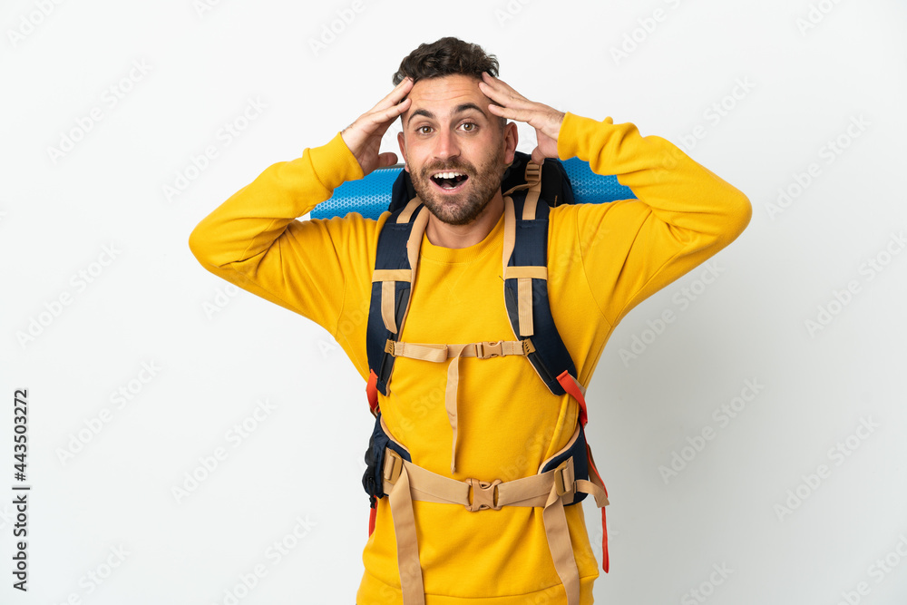 Young mountaineer man with a big backpack over isolated background with surprise expression Young mountaineer man with a big backpack over isolated background with surprise expression