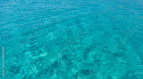 Sea surface blue turquoise color background, some reflections. Calm crystal clear water with small ripples.