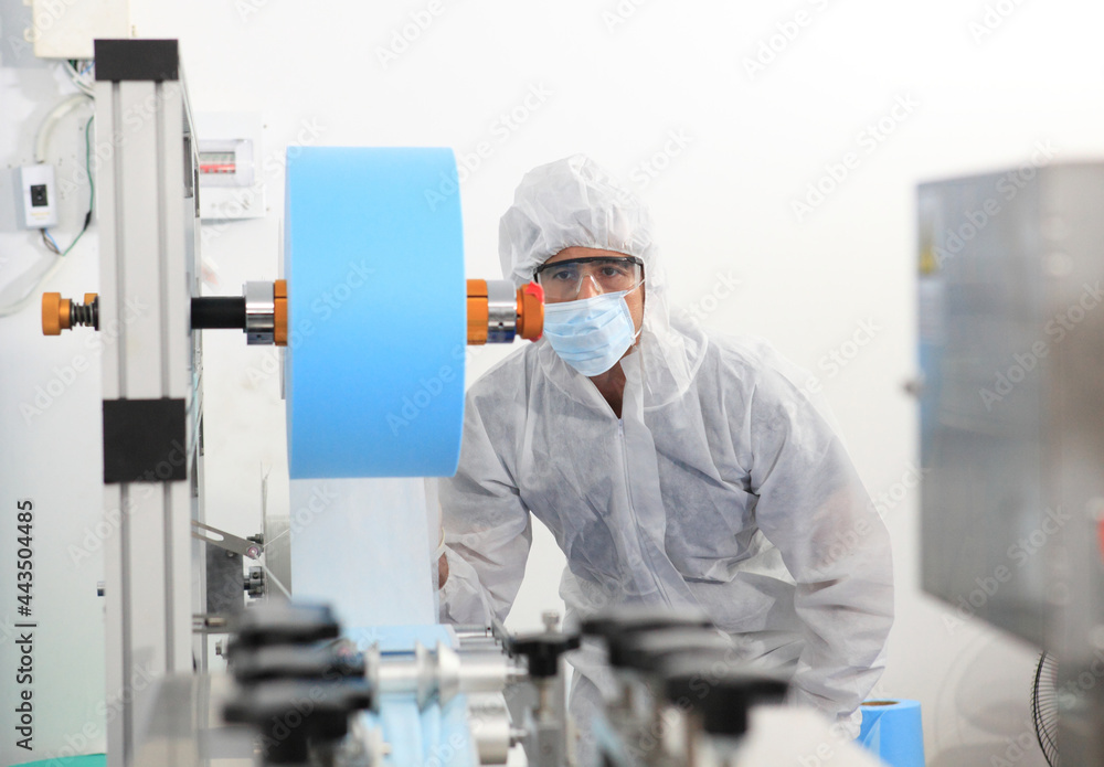 Production engineer with face mask working in factory , Qc engineer checking mask for good quality , Concept of protective action and quarantine to stop spreading of Coronavirus Disease 2019 Production engineer with face mask working in factory , Qc engineer checking mask for good quality , Concept of protective action and quarantine to stop spreading of Coronavirus Disease 2019