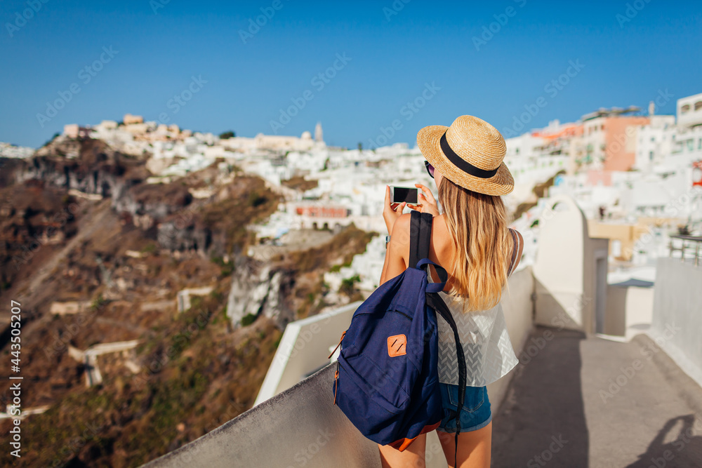 Santorini traveler woman taking photo of Thera, Fira village architecture on phone. Tourism, traveling, summer vacation