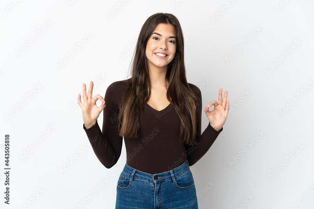 Teenager Brazilian girl isolated on white background showing ok sign with two hands Teenager Brazilian girl isolated on white background showing ok sign with two hands