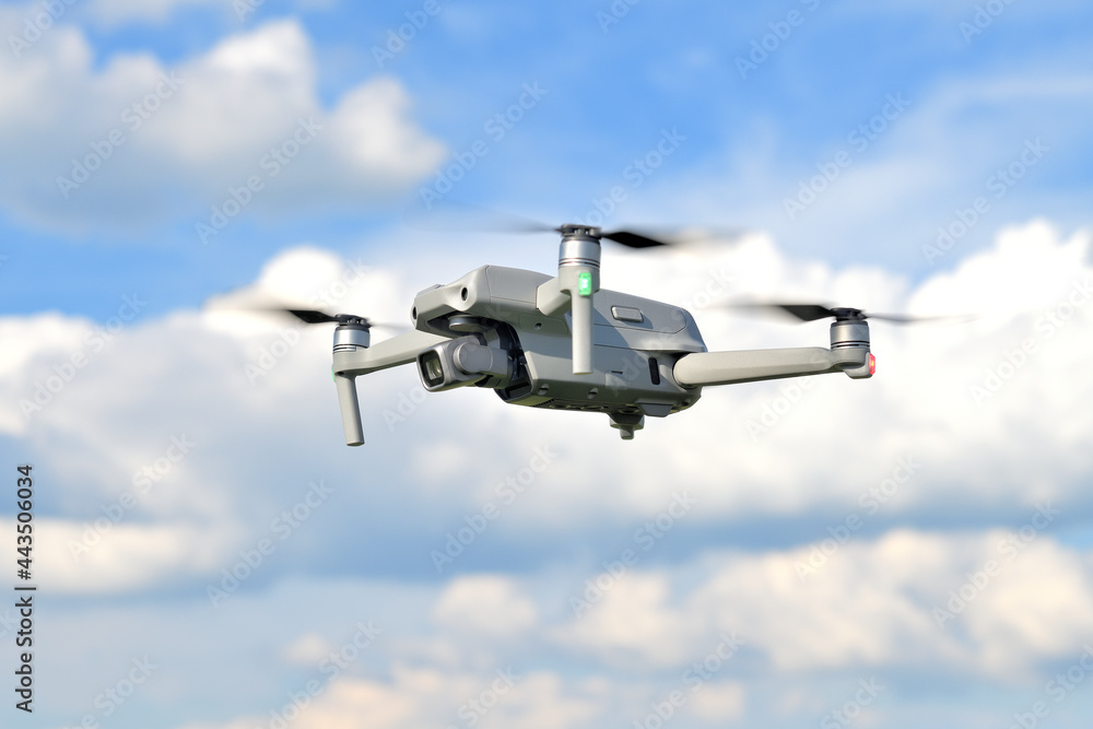 Flying drone quadcopter closeup side view with a blue sky background. UAV drone copter flying with digital camera. View of a photography drone on a blue sky. Flying drone quadcopter closeup side view with a blue sky background. UAV drone copter flying with digital camera. View of a photography drone on a blue sky.