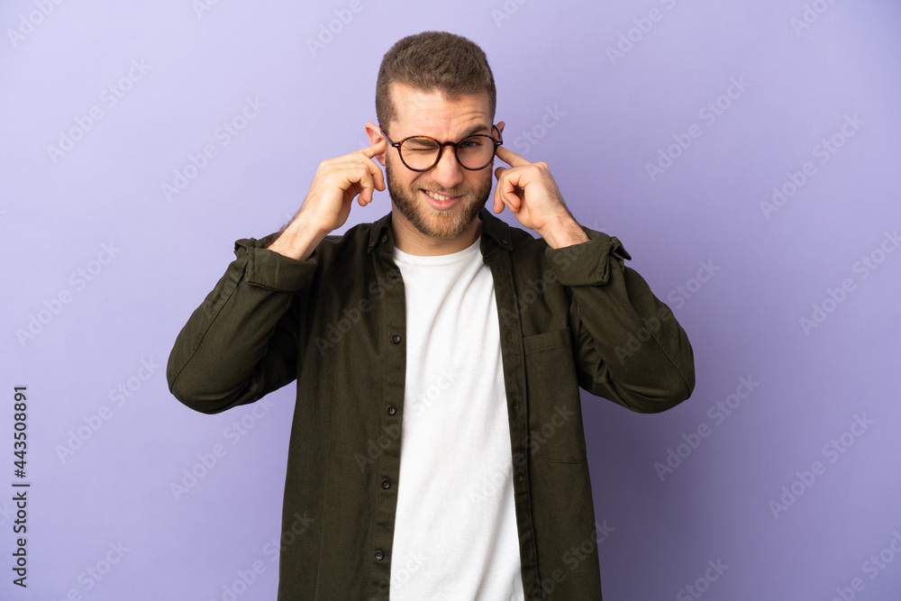 Young handsome caucasian man isolated on purple background frustrated and covering ears Young handsome caucasian man isolated on purple background frustrated and covering ears