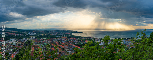 Panoramic view from public park over Huskvarna city and lake Vattern in summer season. Heavy rain can be seen over the lake.