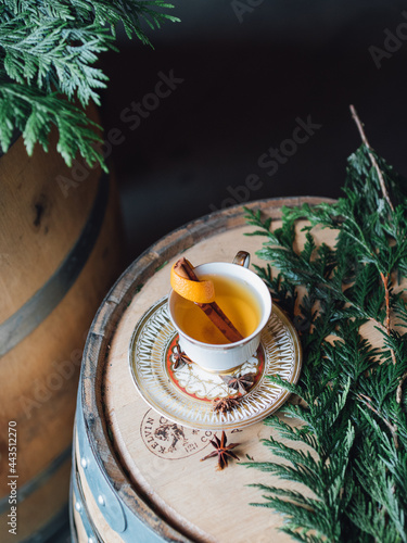vintage saucer with teacup hot toddy cinnamon orange star anise on wood bourbon barrel with wreath making supplies