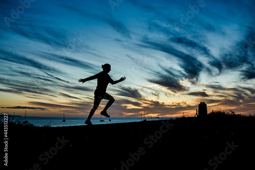 Sport woman doing workout session running on the beach at summer sunset - Focus on silhouette