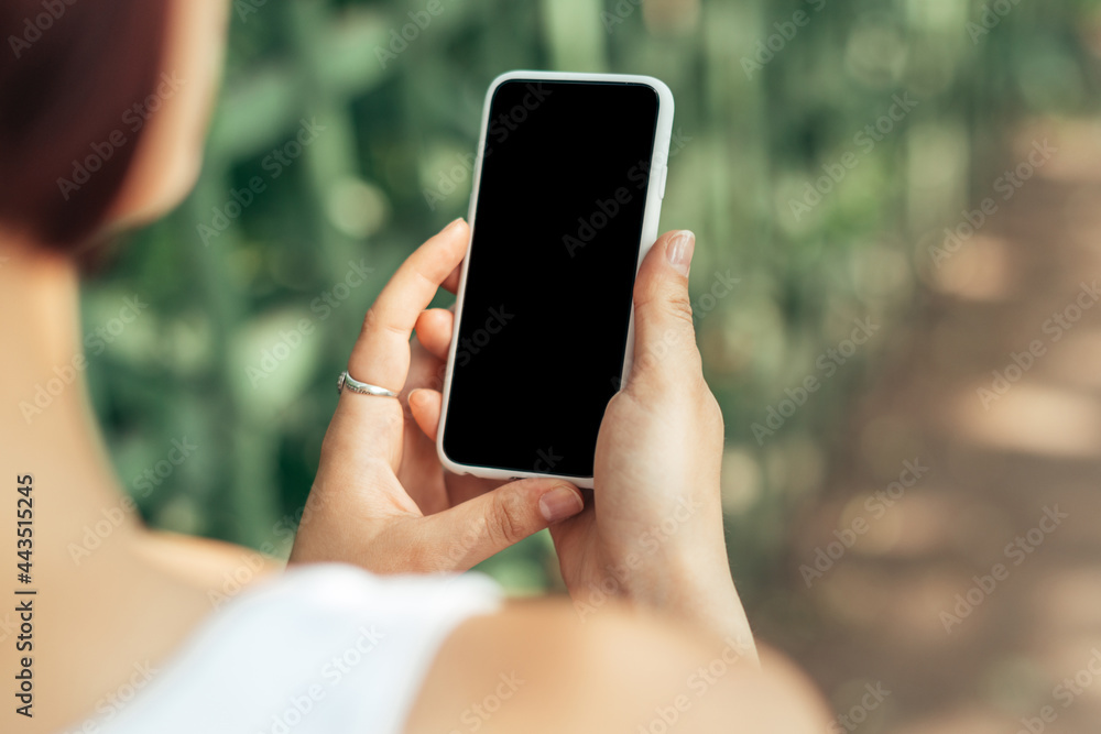 Girl holding smartphone while walking in the park with copy space Girl holding smartphone while walking in the park with copy space