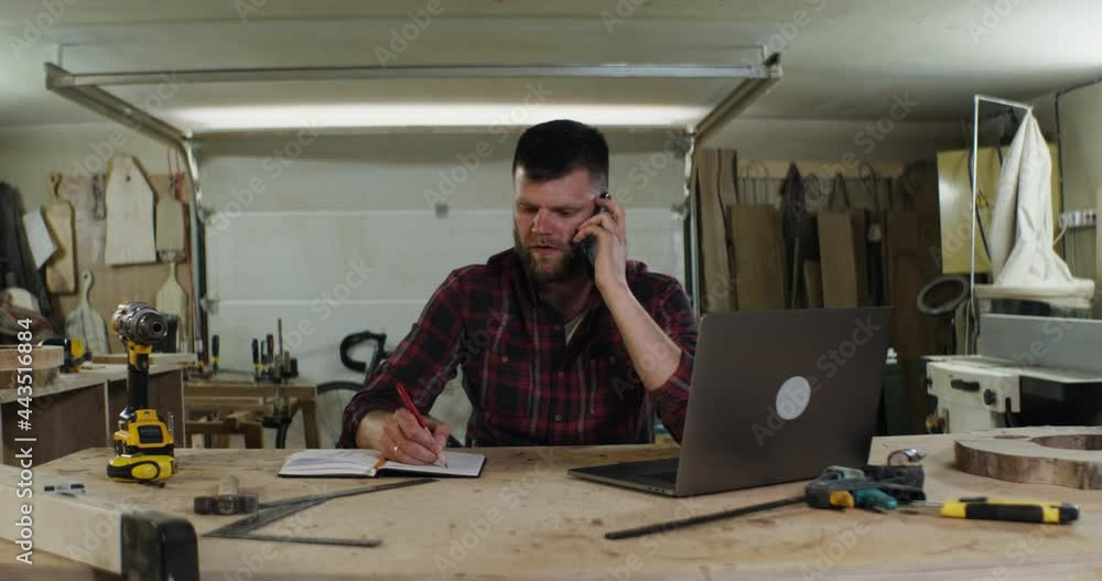 a serious man of European appearance talking on the phone in a carpenter's shop a serious man of European appearance talking on the phone in a carpenter's shop