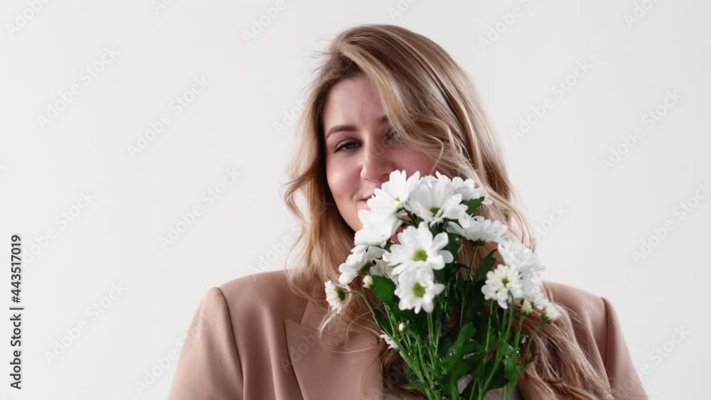 Romantic surprise. Online dating. Body positive. Natural holiday present. Happy shy smiling overweight obese woman with white flower bouquet isolated on light. Romantic surprise. Online dating. Body positive. Natural holiday present. Happy shy smiling overweight obese woman with white flower bouquet isolated on light.