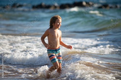 Boy kid jumping in sea waves. Jump by water sea splashes. Summer kids vacation.