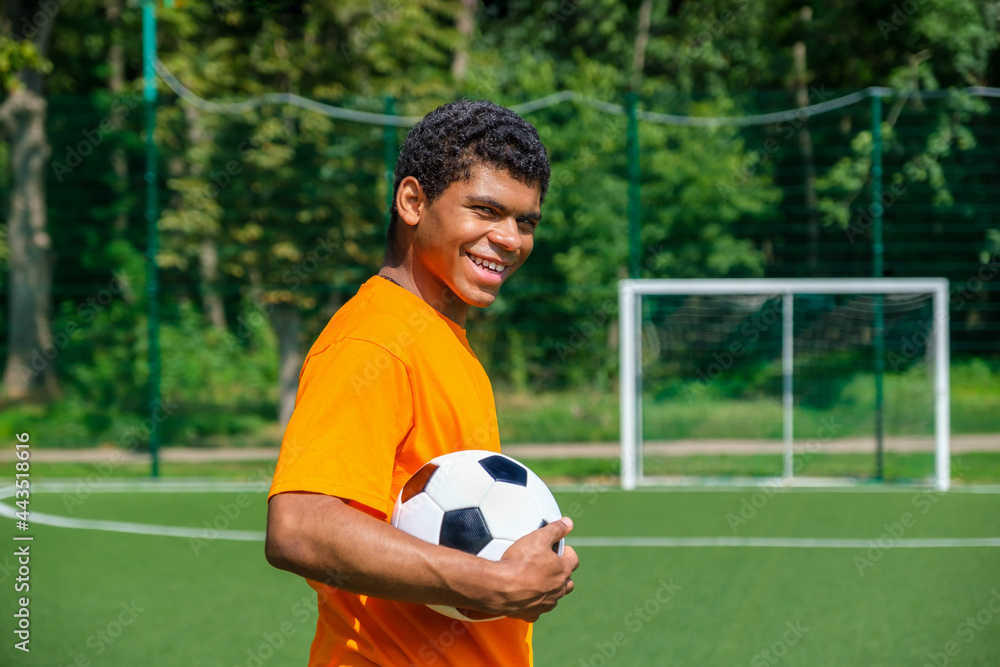 African-American man holding soccer ball while standing on sports court African-American man holding soccer ball while standing on sports court