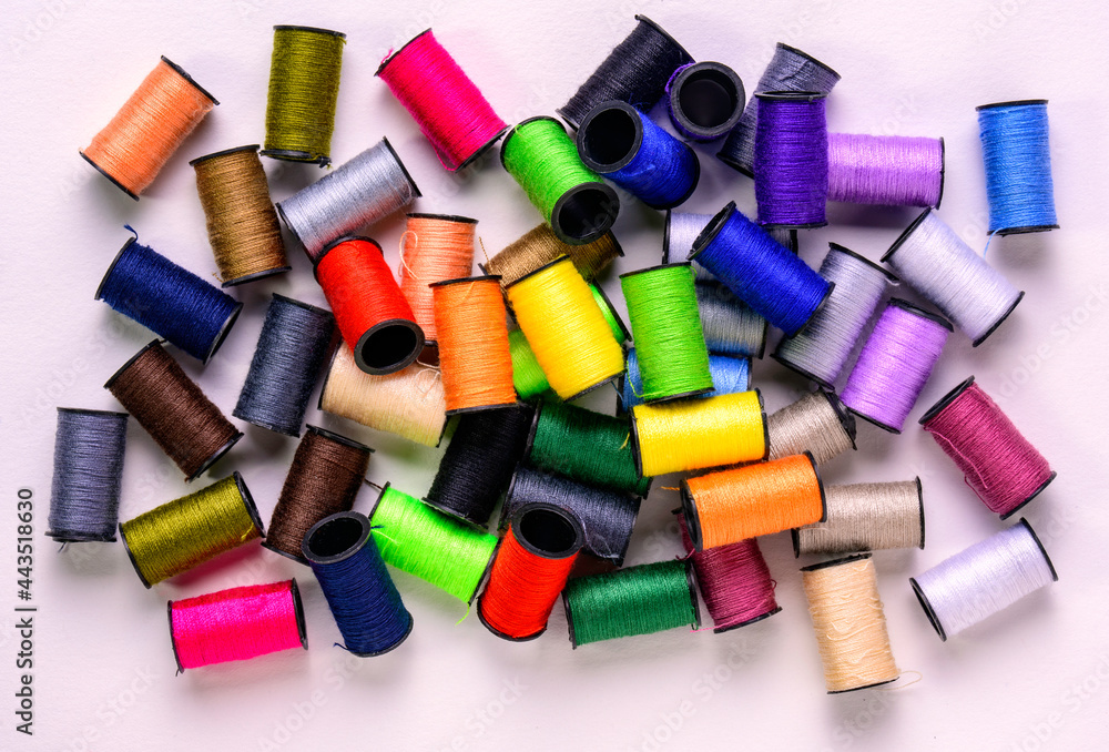 close up of colourful cotton spools in a pile on white close up of colourful cotton spools in a pile on white