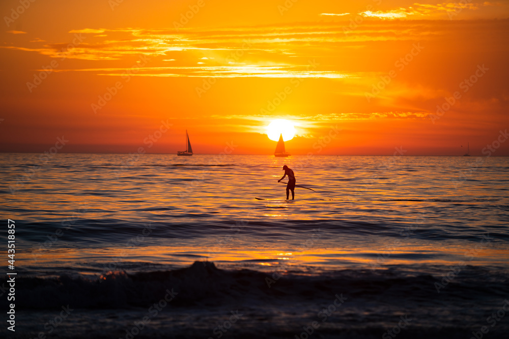 Paddle boarding. Ocean sunset on sky background with colorful clouds. Calm sea with sunrise sky.