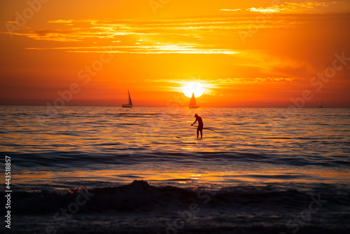 Paddle boarding. Ocean sunset on sky background with colorful clouds. Calm sea with sunrise sky.