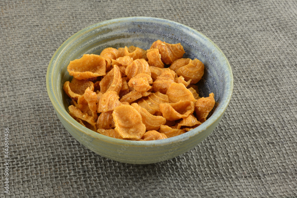 Conch shell shaped crunchy snack made from peanuts, coconut cream ans sesame seeds in ceramic snack bowl on burlap Conch shell shaped crunchy snack made from peanuts, coconut cream ans sesame seeds in ceramic snack bowl on burlap