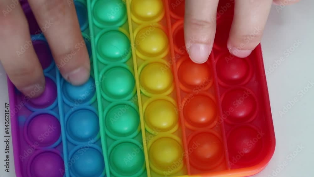 Hands play with antistress pop it toy. Rainbow sensory fidget isolated on white background. New trendy silicone toy. Push pop bubble Silicone fidget toys. Hands play with antistress pop it toy. Rainbow sensory fidget isolated on white background. New trendy silicone toy. Push pop bubble Silicone fidget toys.