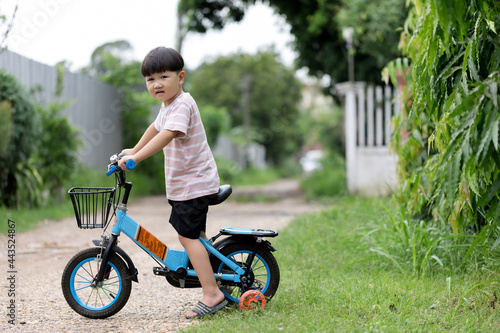 Asian child on a bike ride in the autumn park. Happy smiling child cycling outdoors. Active lifestyle, hobby.