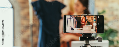 Fotografie Young and beautiful Asian woman blogger showing clothes in front of smartphone c