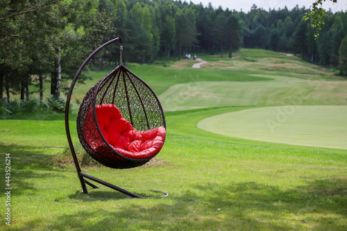 Hanging chair with red plaid on a golf course.  photo