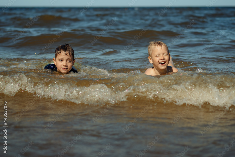 7-8 years old cute caucasian boys swim in the sea with big splashes. Children enjoys swimming in the ocean. Holidays, vacation with kids. 7-8 years old cute caucasian boys swim in the sea with big splashes. Children enjoys swimming in the ocean. Holidays, vacation with kids.
