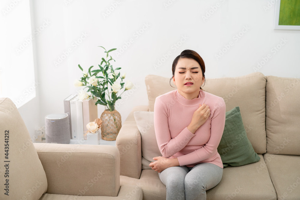 Shot of uncomfortable young woman scratching her arm while sitting on the sofa at home. Shot of uncomfortable young woman scratching her arm while sitting on the sofa at home.