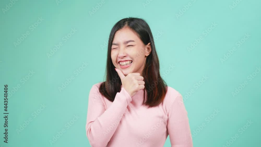 Portrait young Asian happy beautiful woman smiling wear silicone orthodontic retainers on teeth showing thumb up finger isolated on blue background. Dental hygiene and health concept Portrait young Asian happy beautiful woman smiling wear silicone orthodontic retainers on teeth showing thumb up finger isolated on blue background. Dental hygiene and health concept
