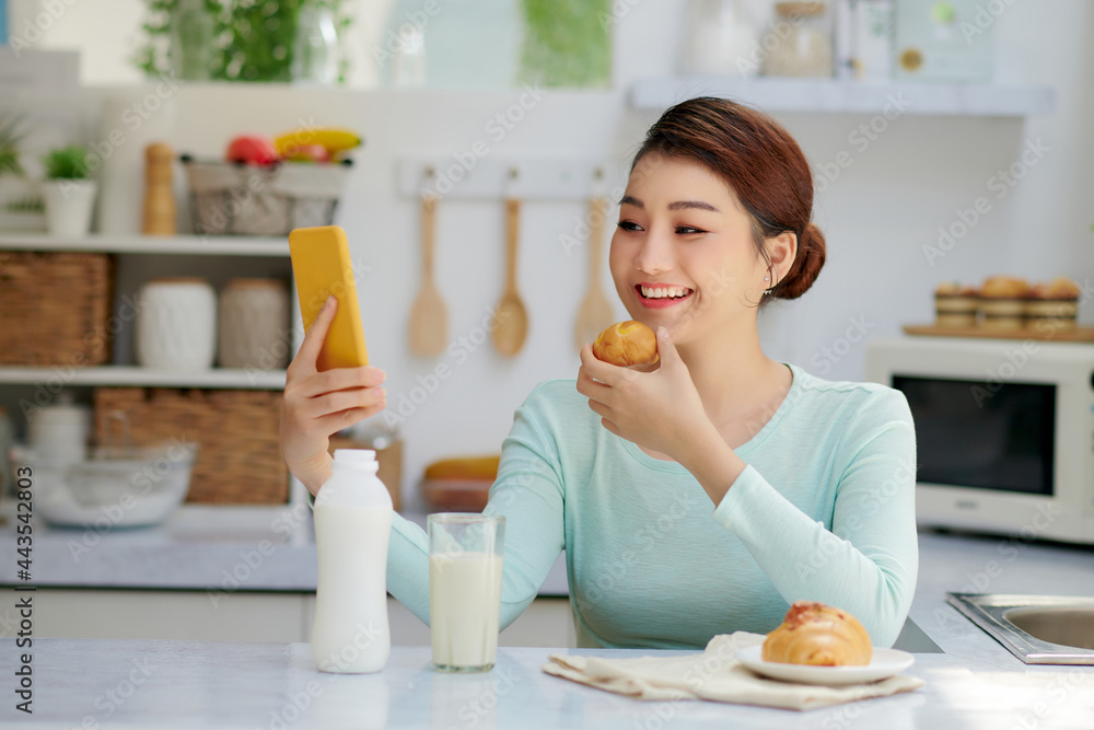 Woman Eating Breakfast Whilst Using Mobile Phone Woman Eating Breakfast Whilst Using Mobile Phone