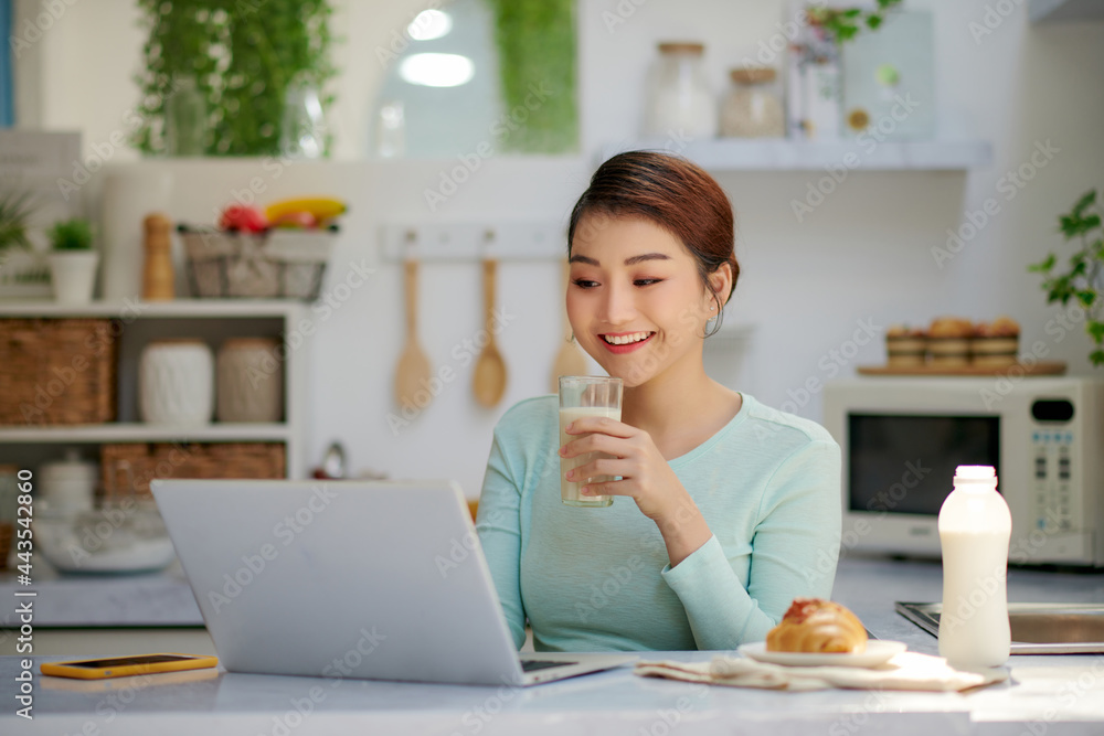 Young attractive asian businesswoman drinking milk while sitting at office desk Young attractive asian businesswoman drinking milk while sitting at office desk