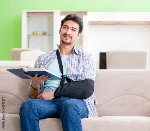 Young student man with hand injury sitting on the sofa