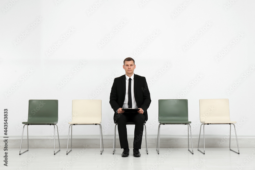 Man with clipboard waiting for job interview in office hall Man with clipboard waiting for job interview in office hall