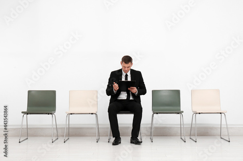 Man with clipboard waiting for job interview in office hall