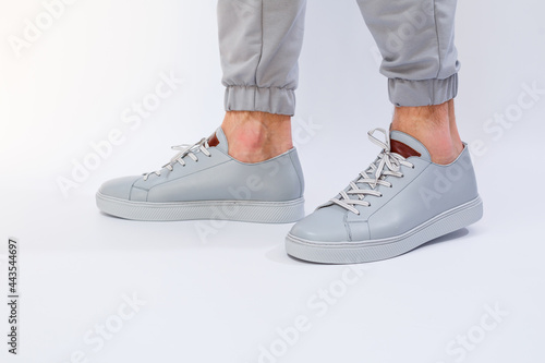 Men's sneakers on a very gray day of natural leather, men's legs shoes in gray leather shoes
