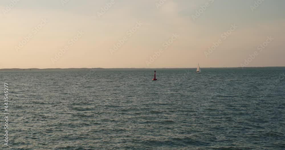 Sea Mark, Navigation Mark Floating In The Sea With Sailboat In Background. - wide, static shot Sea Mark, Navigation Mark Floating In The Sea With Sailboat In Background. - wide, static shot