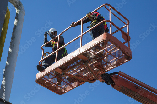 Two male  industry working at high in a boom lift