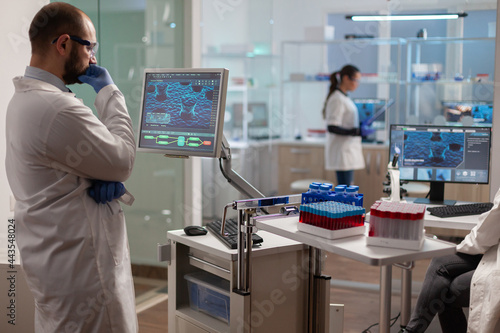 Medical researcher in scientific laboratory analyzing dna sample. Chemical scientis analyzing vaccine on screen examining vaccine development using high tech researching treatment.