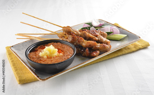 Bbq grilled chicken and beef satay meat stick skewer with cucumber, onion and spicy peanut gravy sauce in dark bar counter background western snack cuisine halal menu