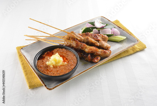 Bbq grilled chicken and beef satay meat stick skewer with cucumber, onion and spicy peanut gravy sauce in dark bar counter background western snack cuisine halal menu