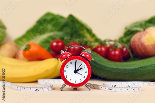 Concept for loosing weight with only eating healthy food at certain times with vegetables, fruits, measuring tape and clock