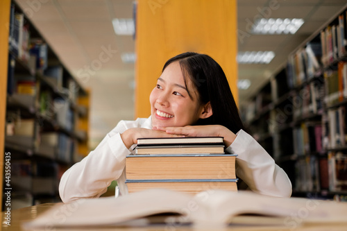 Young Asian women are searching for books and reading books on the tables and aisles of the college libraries to research and develop their academic and education self