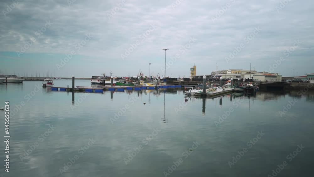 Dock with moored boats and water mirroring the sky with clouds Dock with moored boats and water mirroring the sky with clouds