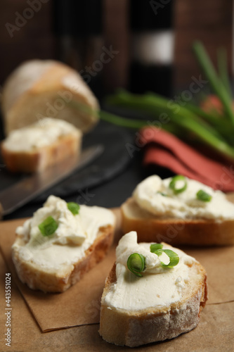 Bread with cream cheese and green onion on table, closeup
