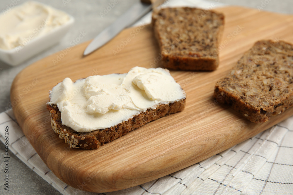 Bread with cream cheese on wooden table, closeup