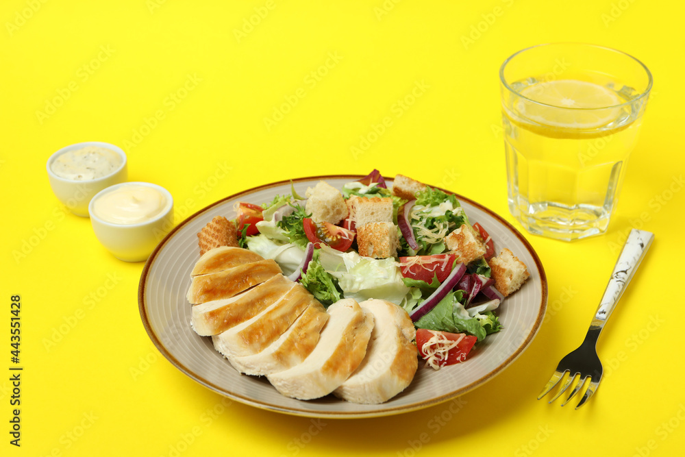 Concept of tasty eating with Caesar salad on yellow background